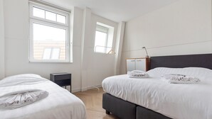 Et moderne soveværelse med to senge, et sengebord, et klædeskab og et vindue.