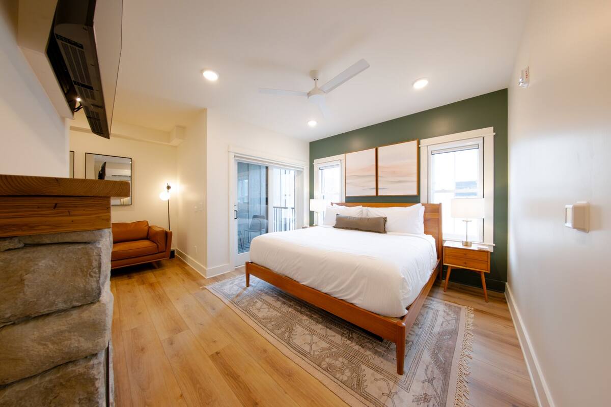 Un dormitorio con una cama de madera, una pared de piedra, un banco de madera y vistas al exterior.