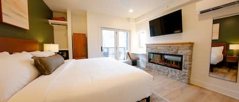 Un dormitorio amplio con una cama grande, una chimenea de piedra, un ventilador de techo y un televisor de pantalla plana montado sobre la chimenea.