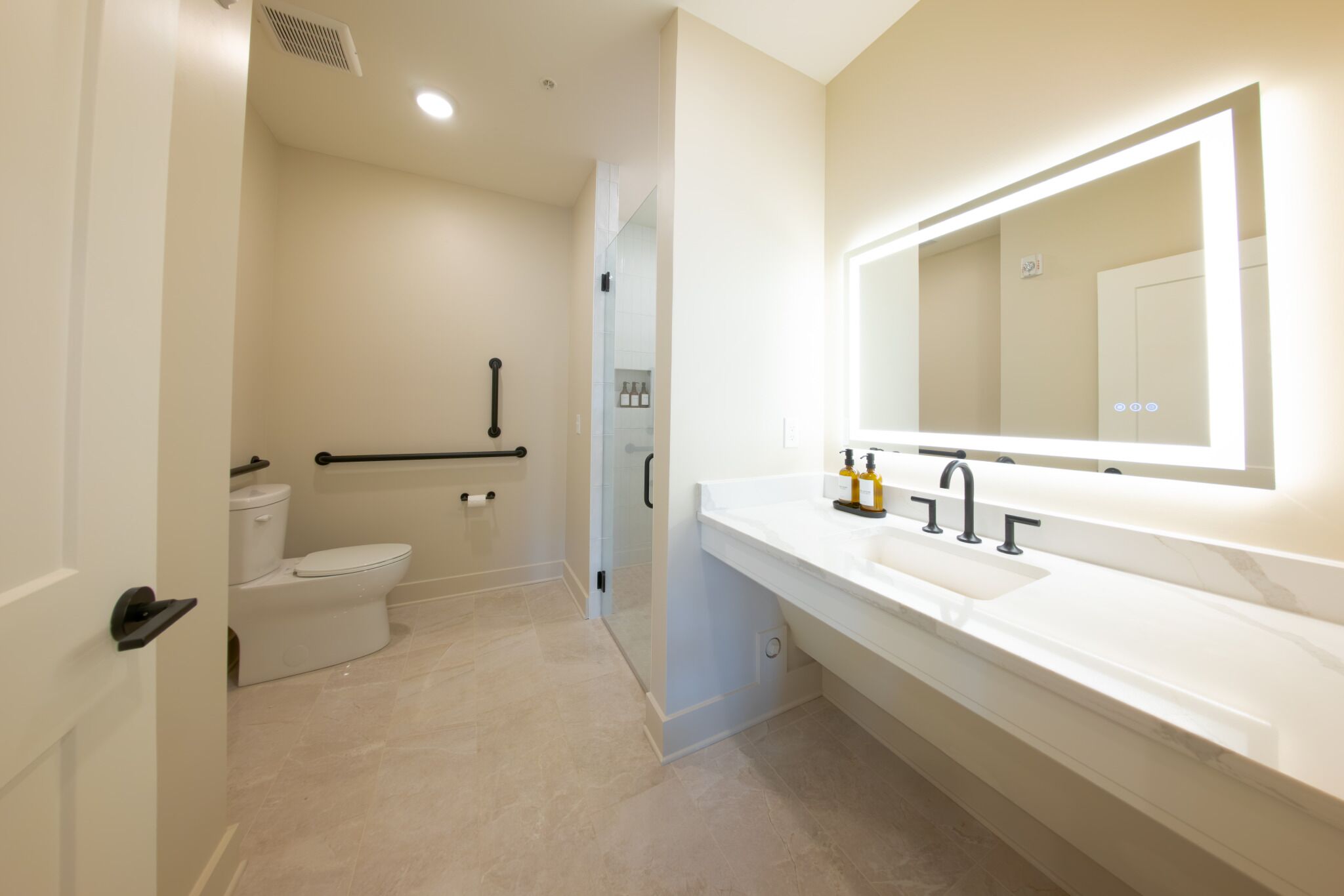A modern bathroom with a toilet, sink, and mirror.