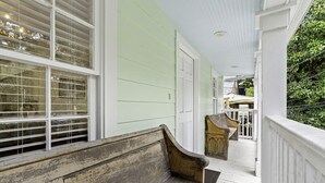 A porch with a wooden bench, a white door, and a window with blinds. - Chic Marigny Retreat Near French Quarter (New Orleans)
