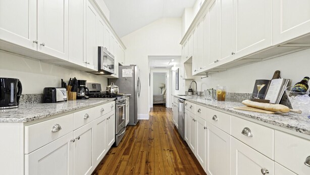 A kitchen with white cabinets, stainless steel appliances, and a wooden floor. - Chic Marigny Retreat Near French Quarter (New Orleans)