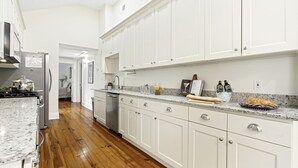 A kitchen with white cabinets, a granite countertop, and a wooden floor. - Chic Marigny Retreat Near French Quarter (New Orleans)