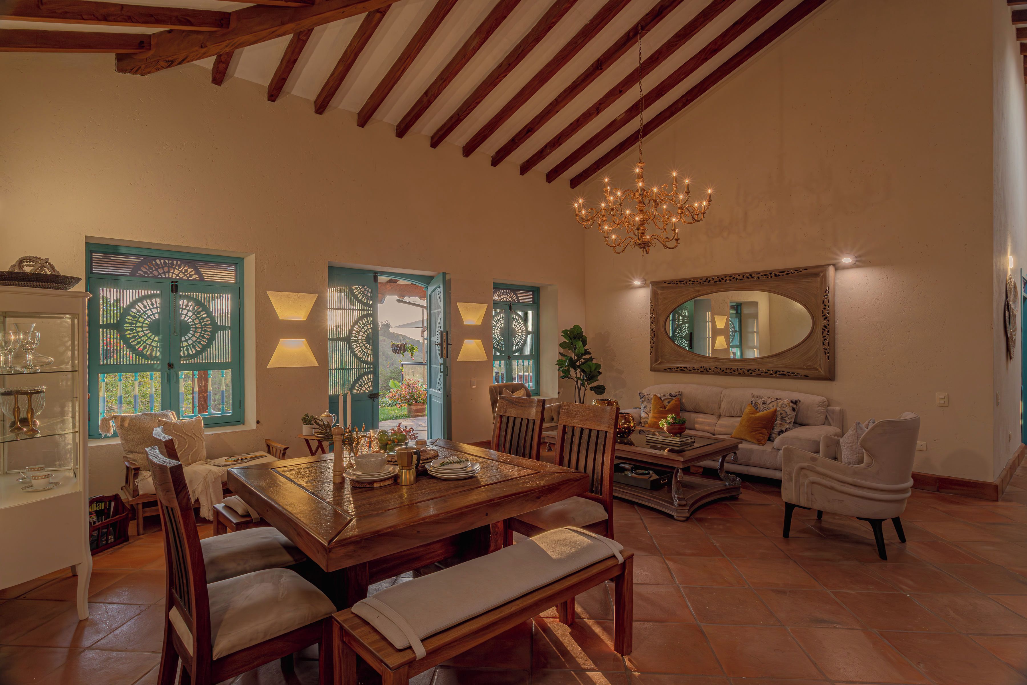 Uma sala de estar ampla com mesa de jantar de madeira, assentos confortáveis e um espelho grande na parede.