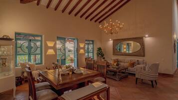 Uma sala de estar ampla com mesa de jantar de madeira, assentos confortáveis e um espelho grande na parede.