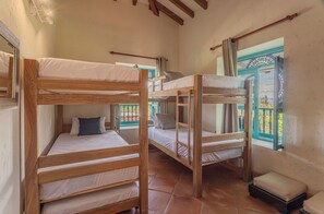 A room with bunk beds, a small stool, and a window with a view.