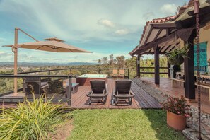 A patio with outdoor furniture, a hot tub, and a view of the landscape.