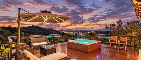 A wooden deck with outdoor furniture, a hot tub, and a view of the landscape.