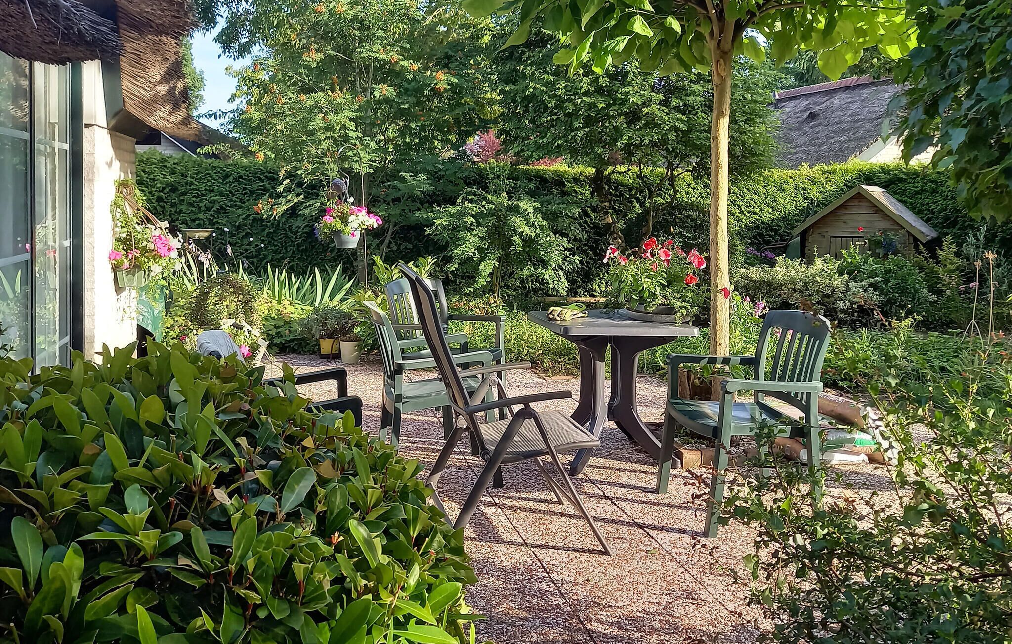 An outdoor seating area with chairs and a table surrounded by lush greenery and flowering plants.