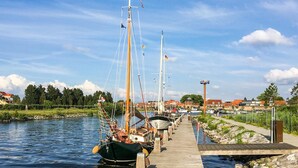 A dock with several boats moored along it, a clear sky, and a town in the background. - Cozy home in Ermelo with WiFi (Ermelo)