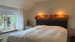 A bedroom with a large bed, two bedside lamps, a small table with a vase of flowers, and a window with curtains. - Cozy home in Ermelo with WiFi (Ermelo)