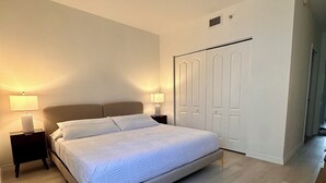 A bedroom with a bed, nightstands, a wardrobe, and a wooden dresser. - Beautiful 2/2.5 Condo w/free parking fast WiFi (Miami)