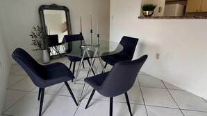 A dining area with a glass table, four dark chairs, a large mirror, and a potted plant. - Beautiful 2/2.5 Condo w/free parking fast WiFi (Miami)
