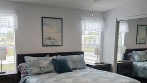 A bedroom with a bed, nightstands, a ceiling fan, and a window with blinds.