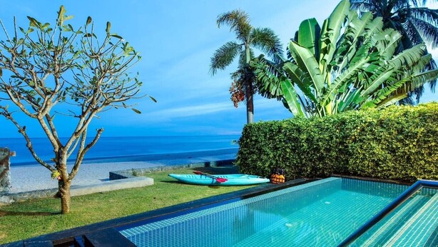 A swimming pool with a view of the ocean, a kayak, and tropical plants. - Peaceful Beachfront Pool Villa – Kui Buri (Bangkok Bo Nok, Kuri Buri)