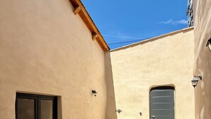 Eine Terrasse im Freien mit Tisch, Stühlen, einer Schiebetür, einer Steinsitzbank und einer Tür.