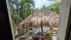 A staircase leading to a covered outdoor area with a thatched roof, stone flooring, and potted plants. - Charming 1-bedroom apartment at La Ropa Beach (Zihuatanejo)