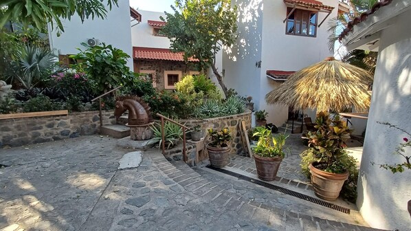 A courtyard with stone steps, potted plants, and a decorative metal sculpture.