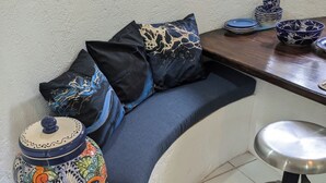A corner seating area with a cushioned bench, a decorative ceramic pot, and a metal stool. - Charming 1-bedroom apartment at La Ropa Beach (Zihuatanejo)