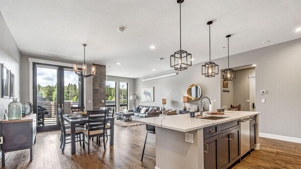 A modern kitchen with a large island, pendant lighting, and a view to the outdoors.