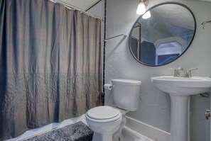 A bathroom with a toilet, sink, and shower curtain. - Carriage House studio min to ECU (Ada)
