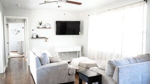 Een moderne woonkamer met een zithoek, een televisie en een plafondventilator.