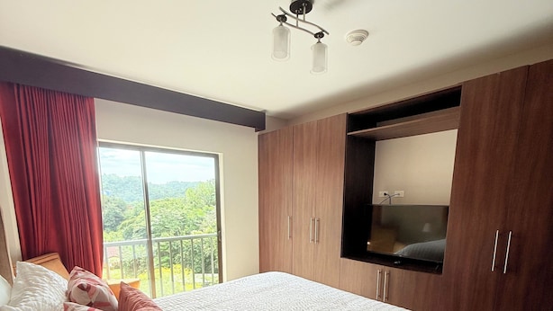 Ein Schlafzimmer mit einem großen Bett, einem Holzschrank und einem an der Wand befestigten Fernseher.