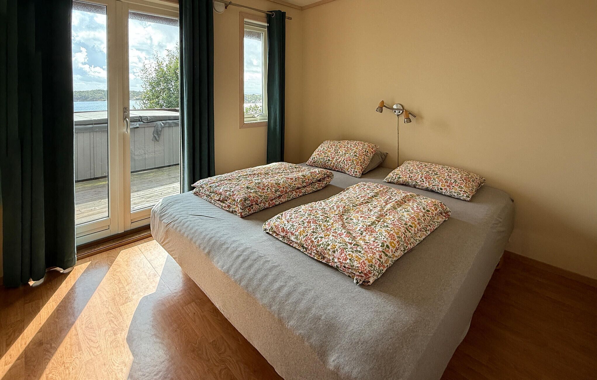 A bedroom with a large bed, two pillows, a nightstand, and a window with curtains.