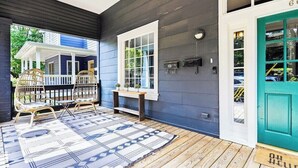 A porch with two wicker chairs, a patterned rug, and a bench. - Stylish Oasis in Prime Location  (Atlanta)