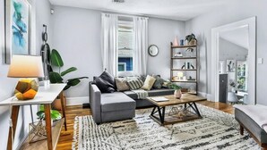 A modern living room with a grey sofa, a coffee table, and a bookshelf. - Stylish Oasis in Prime Location  (Atlanta)