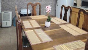 A dining area with a wooden table, chairs, and a flower centerpiece.