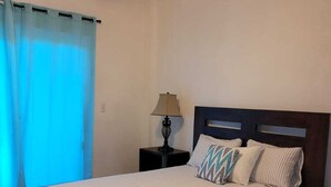 A neatly made bed with striped bedding, a dark wooden headboard, and a nightstand with a lamp.