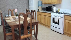 A kitchen with wooden cabinets, a white stove, and a dining table with chairs.