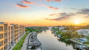 A waterfront hotel with a row of boats docked along the water, a pedestrian walkway, and a view of the sunset over the city skyline. - Waterfront Condo with Pool, Spa, and Fitness Center near Downtown Sarasota (Sarasota)