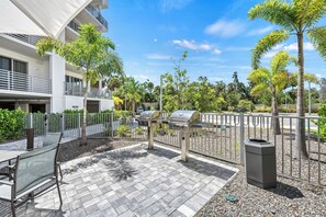 Eine Terrasse im Freien mit Grill, Sitzgelegenheit und einem Gebäude im Hintergrund.