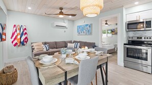 A modern kitchen with a built-in oven and microwave, a dining area with a wooden table and chairs, and a ceiling fan. - CJs - Pet Friendly, Located in Siesta Key Village, Steps to Siesta Key Beach! (Siesta Key)