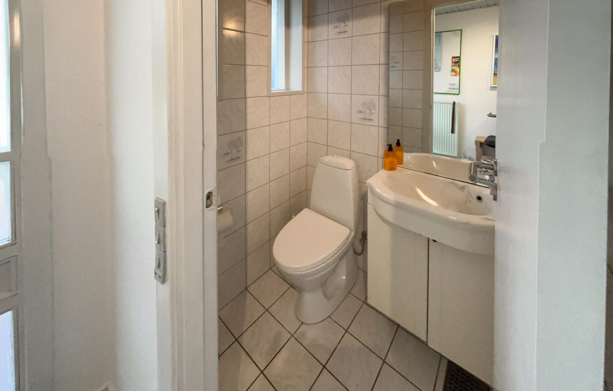 A bathroom with a toilet, sink, and tiled floor.