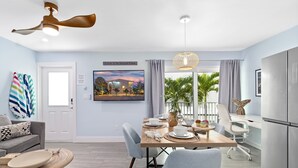 A modern kitchen with a dining area, a ceiling fan, and a view of the outdoors.
