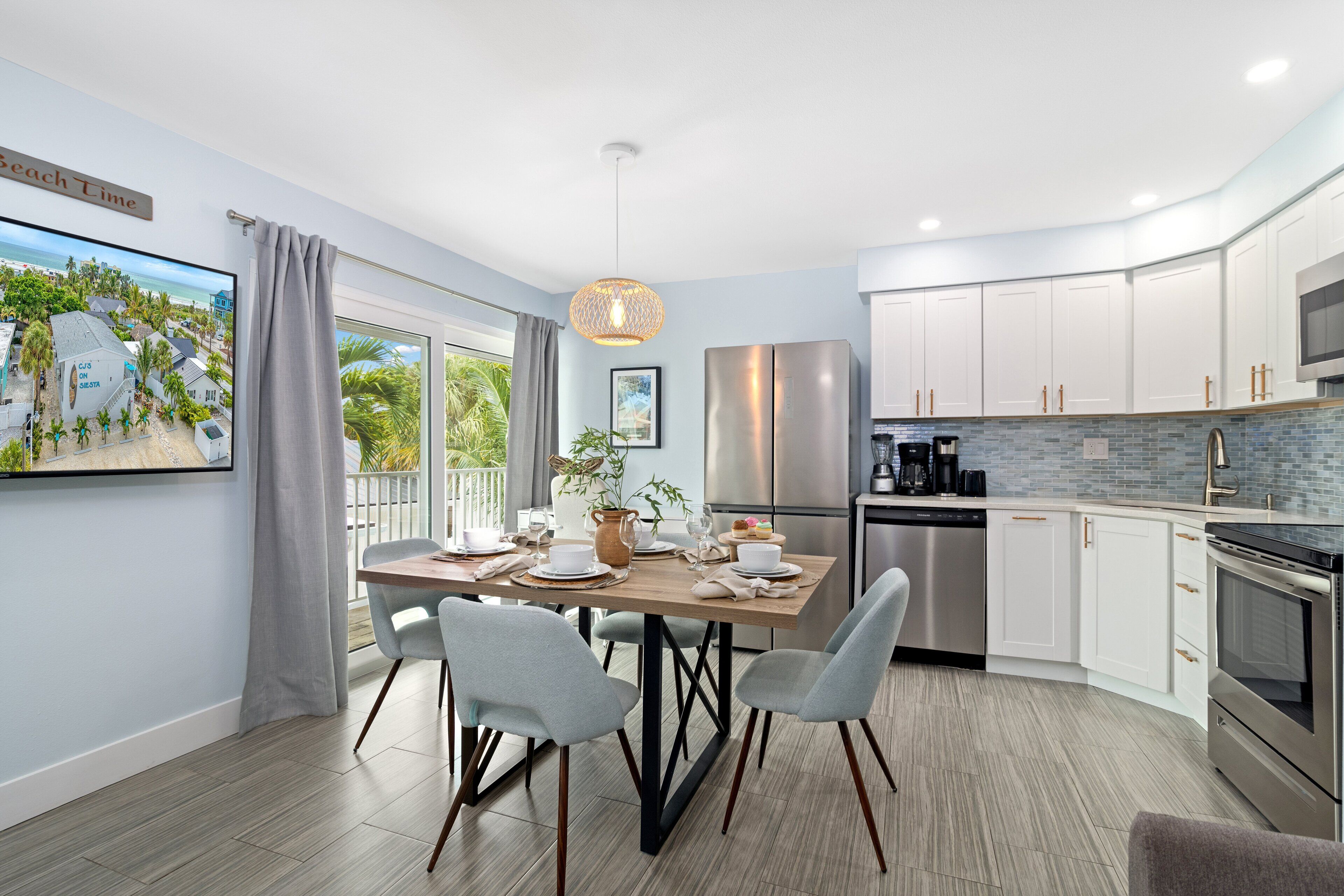 A modern kitchen with a dining area, featuring a large island, stainless steel appliances, and a view of the outdoors.