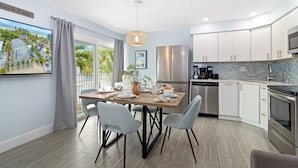 A modern kitchen with a dining area, featuring a large island, stainless steel appliances, and a view of the outdoors.