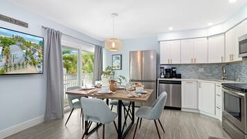 A modern kitchen with a dining area, featuring a large island, stainless steel appliances, and a view of the outdoors.