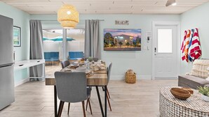 A modern dining area with a wooden table, grey chairs, and a hanging light fixture. - Sea Dream - Pet Friendly, Located in Siesta Key Village, Steps to Siesta Key Beach! (Siesta Key)