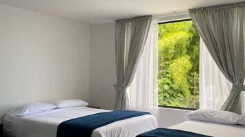 A hotel room with two beds, a large window with curtains, and a ceiling light.