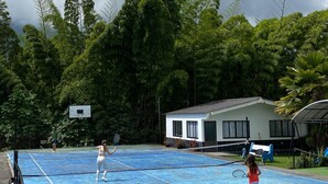 An outdoor tennis court surrounded by lush greenery and a small building. - Finca Hotel Los Alpes, 15 minutes from downtown, surrounded by nature. (Manizales)