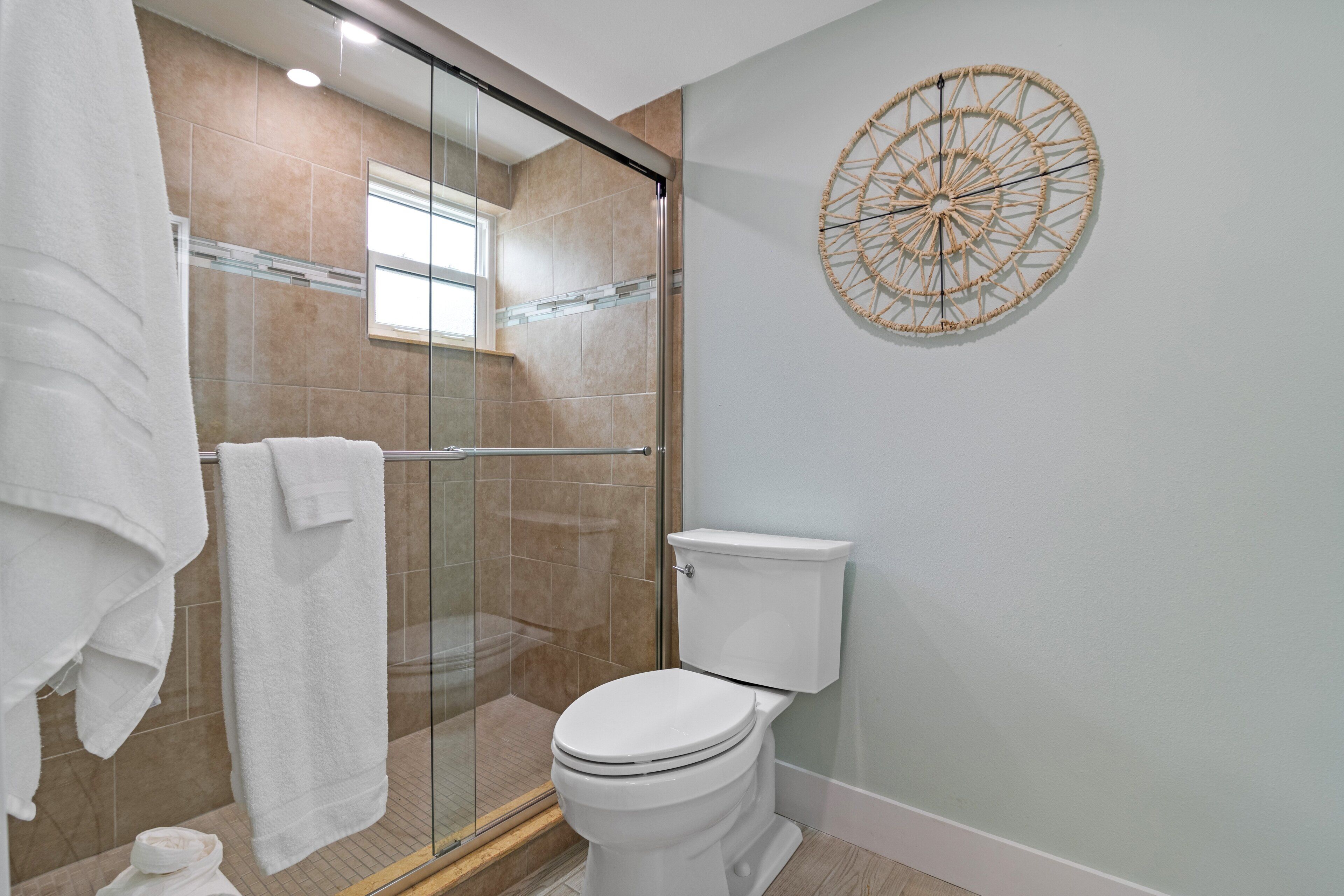Een badkamer met een douchecabine, een toilet en een decoratief object aan de muur.