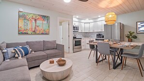 A modern living room with a gray sofa, a round coffee table, and a dining area with a wooden table and chairs. - Sea Escape - Pet Friendly, Located in Siesta Key Village, Steps to Siesta Key Beach! (Siesta Key)