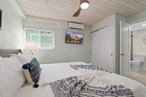 Quarto com cama, televisão, ar condicionado, porta e janela.