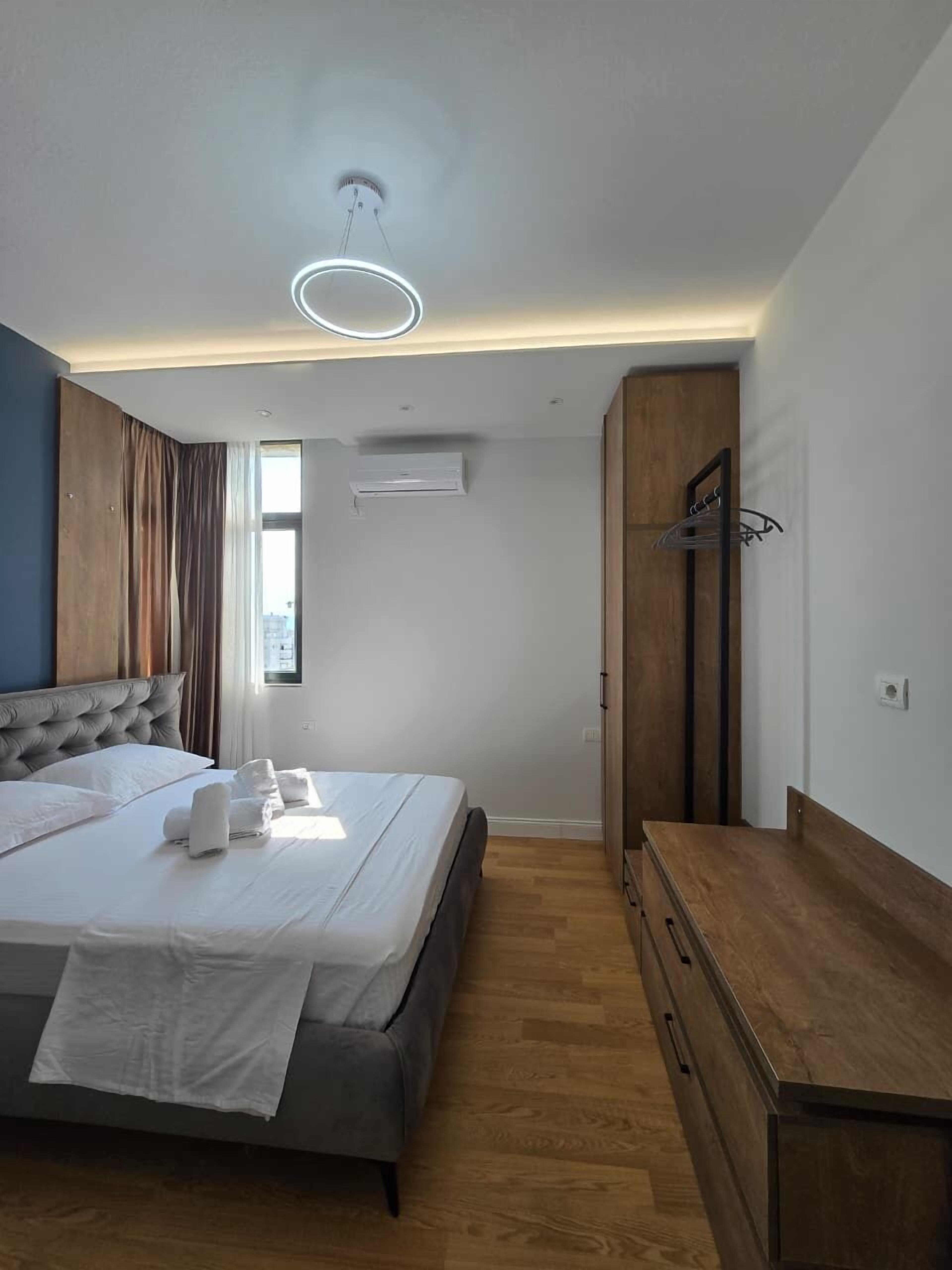 Ein modernes Schlafzimmer mit einem Bett, einer Holzkommode und einer Klimaanlage.