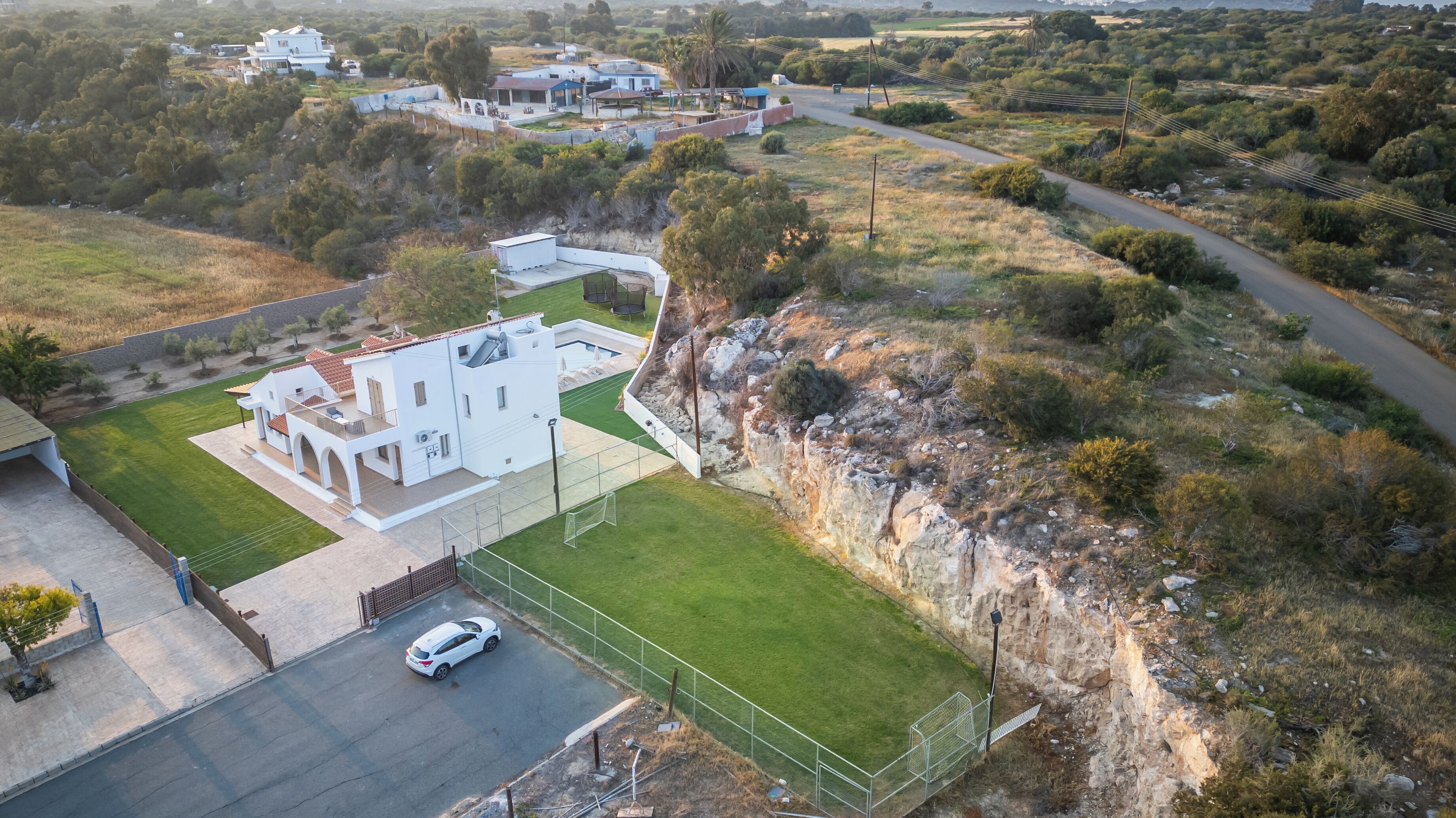 Vista aérea de una casa moderna con un amplio césped, una entrada para vehículos y un paisaje circundante.
