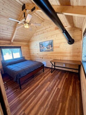 Une chambre confortable dans un chalet, avec un lit, une table et un tableau représentant un élan accroché au mur.
